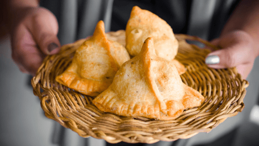 a hand holding a basket of bread