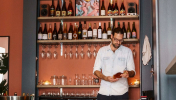 a man standing next to a bottle of wine